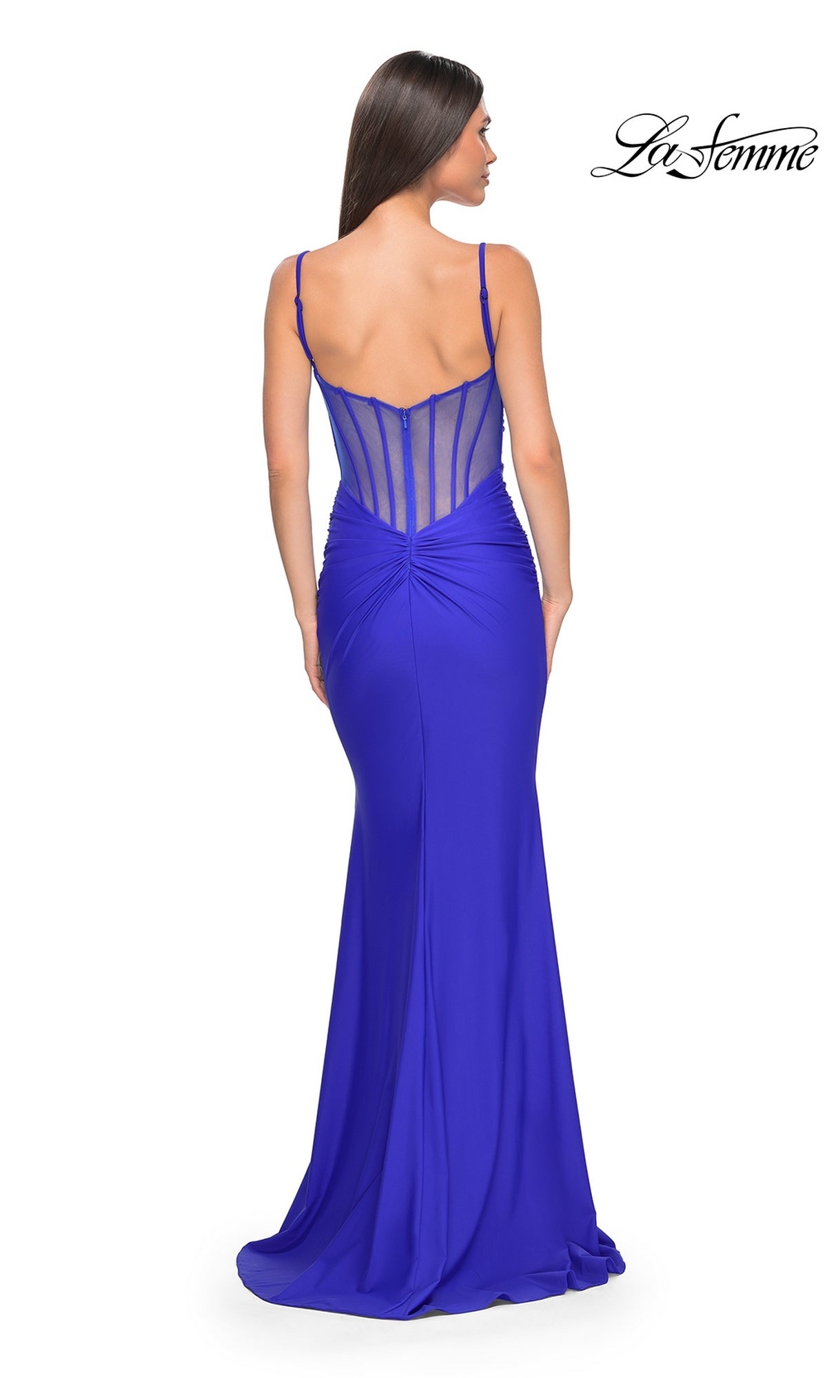 A woman faces away in the La Femme Sheer-Back Long Jersey Prom Dress 32153, royal blue with a sheer corset-style back and ruched details, shown against a plain white background.